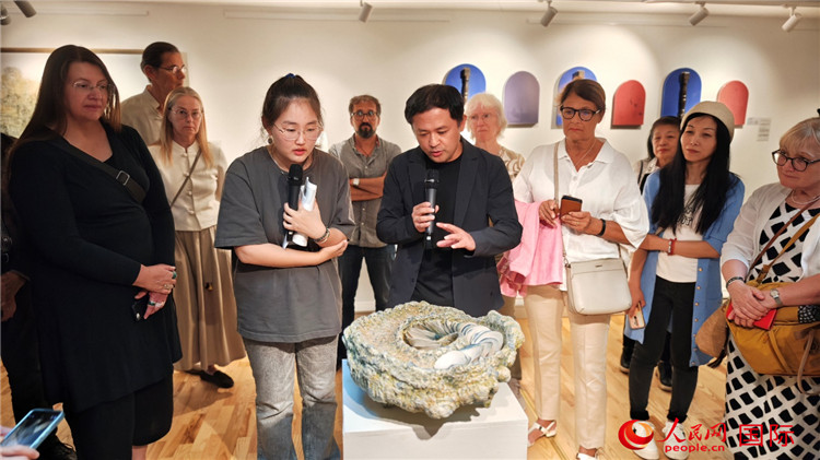 參展人、景德鎮(zhèn)陶瓷大學(xué)設(shè)計(jì)藝術(shù)學(xué)院副院長(zhǎng)余劍峰（中）向來(lái)賓介紹參展作品。人民網(wǎng)記者 殷淼攝